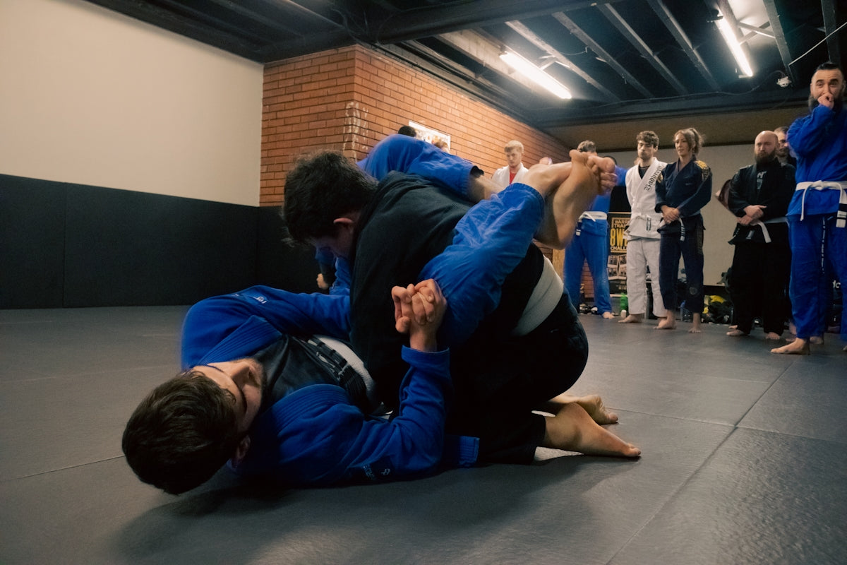 two men in blue and black suits are fighting in a gym
