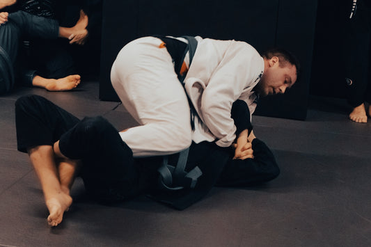 a man in white shirt and black pants on a black mat