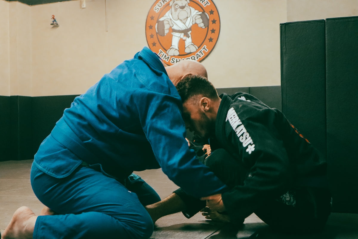 a man in a blue shirt and a man in a black jacket in a gym