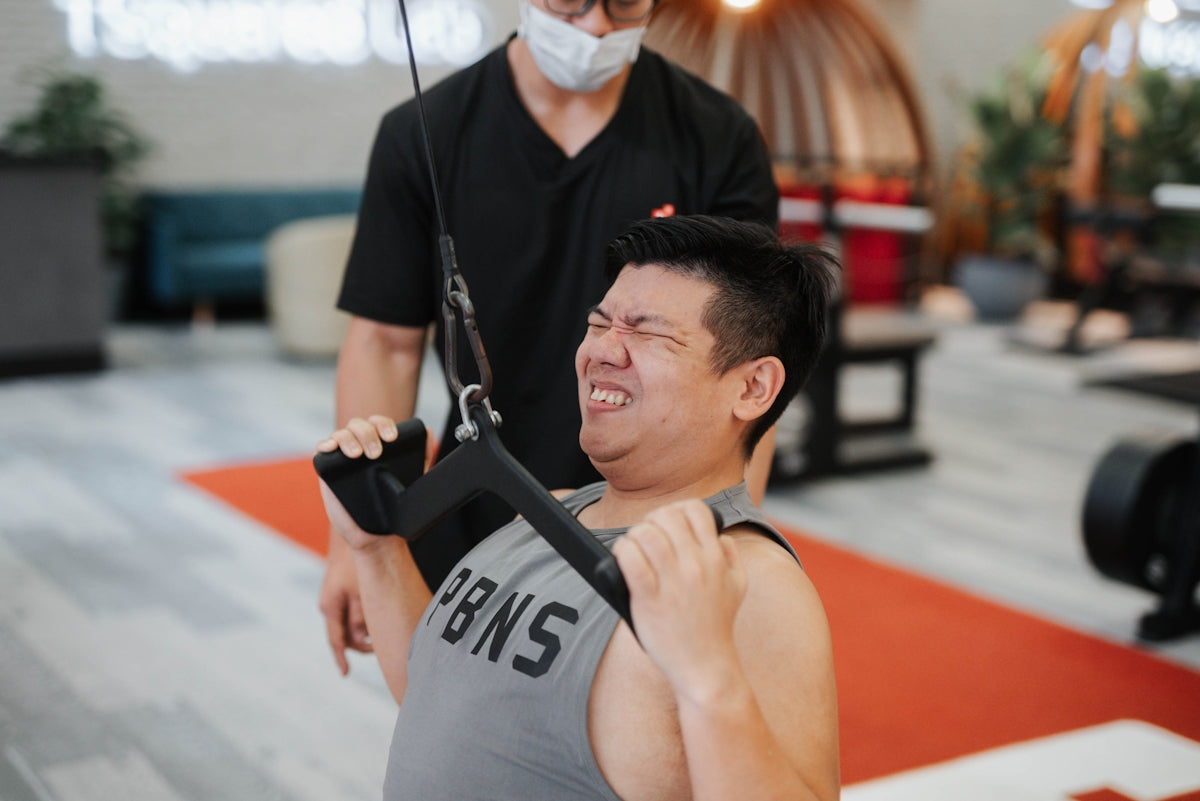 Man straining while doing a cable pull exercise.