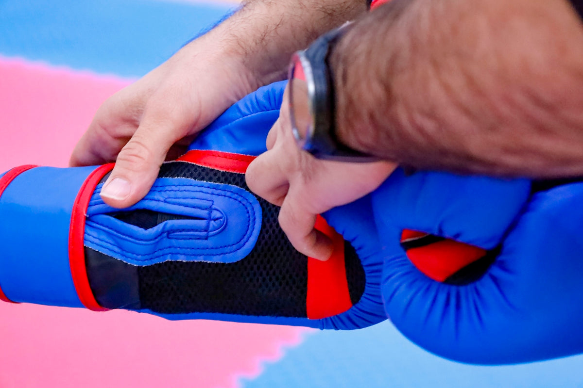 a man is putting on a blue and red glove