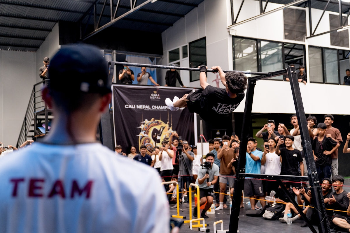 A man doing a trick on a bar in front of a crowd