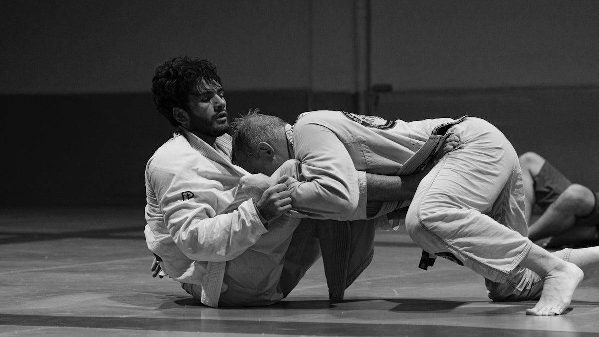 A man holding a baby on his back in a gym