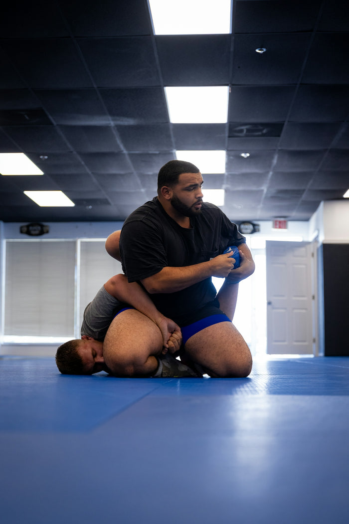 Two men wrestling on a blue mat