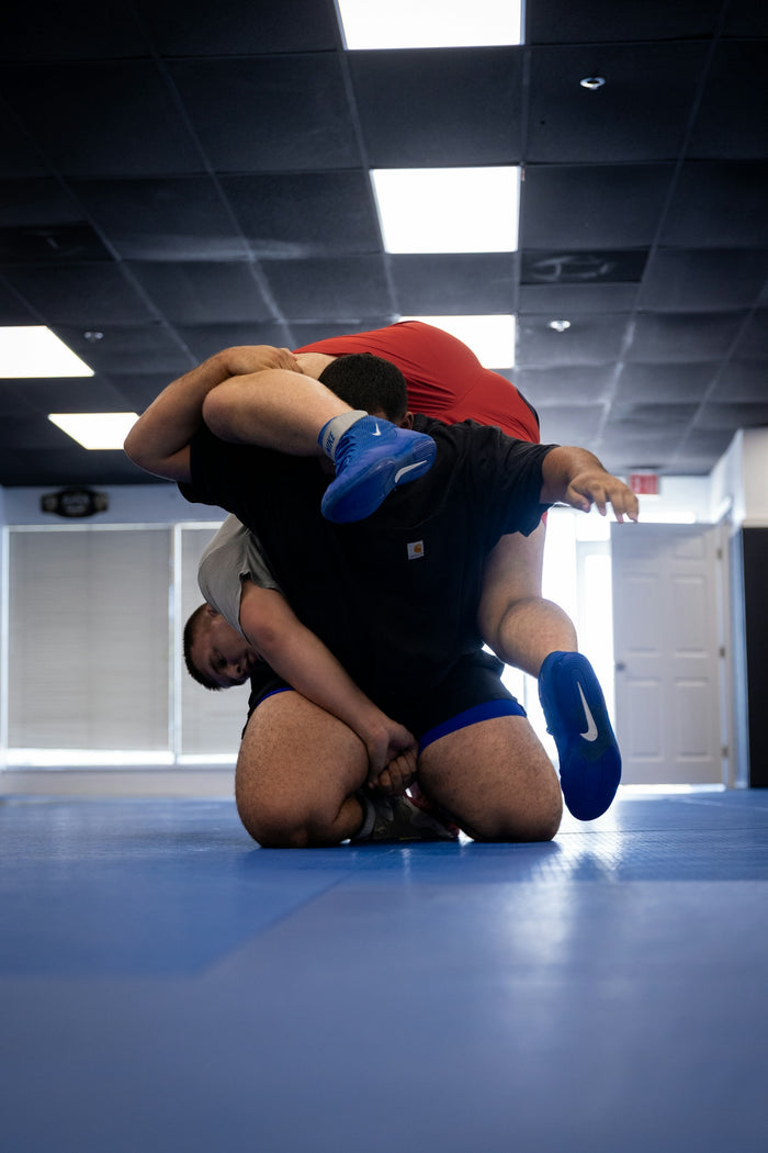 Two men wrestling on a blue mat
