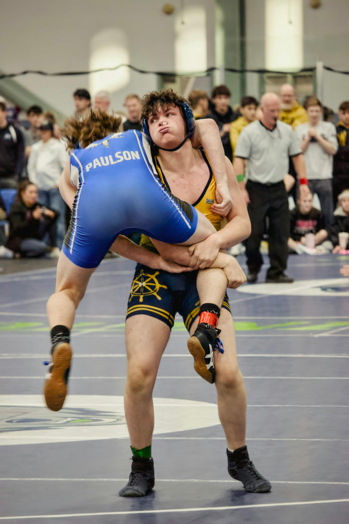 Two wrestlers grappling intensely during a match