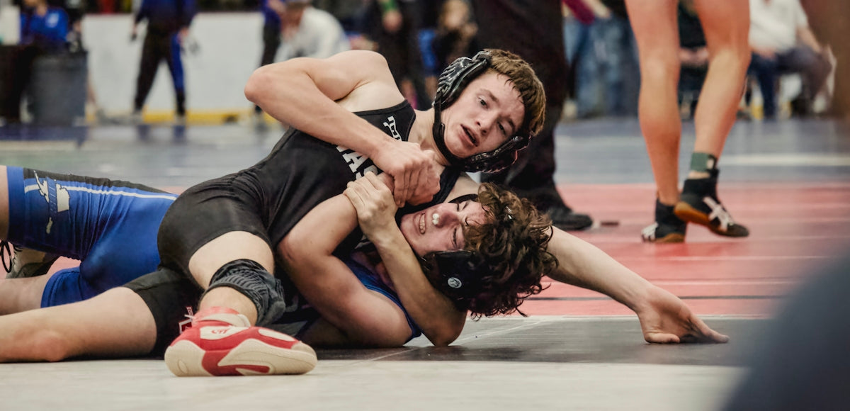 Two young men wrestling on a mat